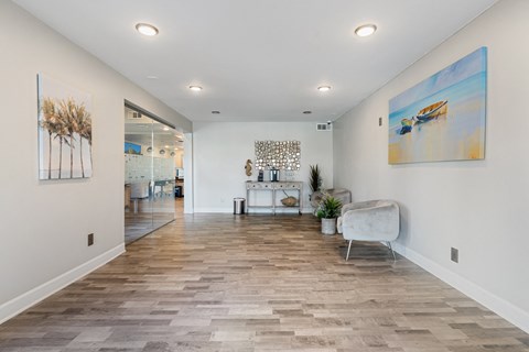 the living room with white walls and wood flooring and a white couch and chair